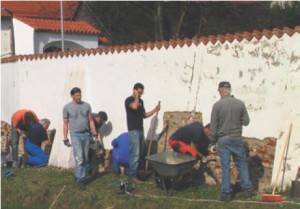 Gemeindemitglieder schlagen — unter fachlicher Anleitung — nicht mehr haftenden Putz vom jahrhundertealten Mauerwerk der Friedhofsmauer herunter. (Foto: Michael Rottmann)
